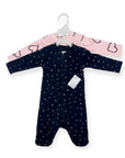 Navy baby onesie with white polka dots on a hanger against a white background