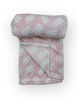 Folded pink blanket with white paw prints on a white background