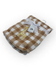 Checkered blanket with a giraffe design and tag on a white background