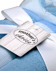 Close-up of a 'mother's choice' label on a blue blanket with white ribbons.