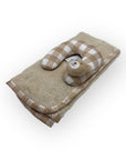 Baby pillow with checkered design and teddy bear toy on a beige towel