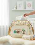 Stork And Baby beige nappy bag with 'Lil Friends' embroidery and animal graphics. Features spacious compartments and a lightweight design.