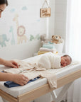 Stork And Baby boys 2 piece embroidered muslin set in beige with blue pants. Newborn baby wrapped in white blanket.