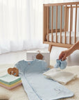 Stork And Baby light blue cotton baby sleeping bag with star embroidery, matching booties, and nursery accessories.