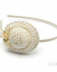 Stork And Baby cream girls alice band featuring a miniature hat adorned with pearls, iridescent beads, and a ribbon rose