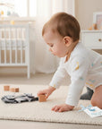 Stork And Baby grey ribbon infant socks with a baby playing on a rug.