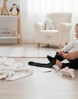 Stork And Baby Infants black leggings, soft stretchy fabric for comfort and movement. A baby is being dressed.