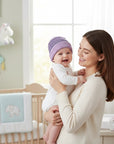 Stork And Baby purple striped knit infants winter hat on a smiling baby held by a mother.