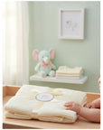 Stork And Baby Mothers Choice beige 100% cotton baby shawl with diamond knit texture, tied with a ribbon on a table.