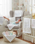 Stork And Baby Mothers Choice 3 piece cot sheet set in white with embroidered baby text in a cozy nursery setting.