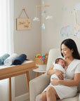Stork And Baby mother holding a newborn swaddled in a Mothers Choice grey dinosaur flannel receiver in a nursery