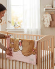 Stork And Baby Mothers Choice pink infants cutwork blanket with a cute bear design, draped over a wooden baby cot.