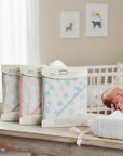 Stork And Baby Mothers Choice cotton muslin hooded receivers in blue, pink, and grey with a newborn in a nursery.