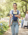 Stork and Baby navy 4-way baby carrier with adjustable straps, worn by a woman walking outdoors.