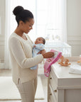 Stork And Baby pink burp cloth set with embroidered details, held by a woman with a baby.