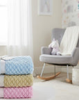 Stork And Baby plush and cozy nursery blankets in blue with white polka dots, green, and pink.
