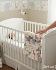 Stork and Baby white polyester baby blanket with pink, grey, and gold unicorn pattern, tied with a grey ribbon.
