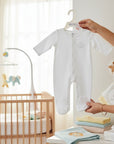 Stork And Baby white cotton babygrow with snap closure and embroidered cotton detail. Newborn essentials.