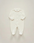 Stork And Baby white footed romper with silver embroidery detail on chest. Long sleeves, collared neckline, and button front.