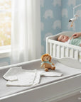 Stork And Baby white knit infant cardigan with button front and soft fabric. A plush lion toy sits nearby.