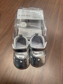 Pair of baby shoes in a clear plastic packaging on a wooden surface