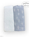 Two baby blankets, one white and one blue with tree pattern, on a white background.