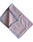 Pink blanket with gray trim on a white background