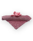 Pink textured blanket with a small pink plush toy on a white background