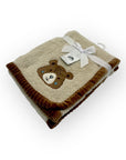 Folded blanket with a teddy bear design and a white ribbon on a white background