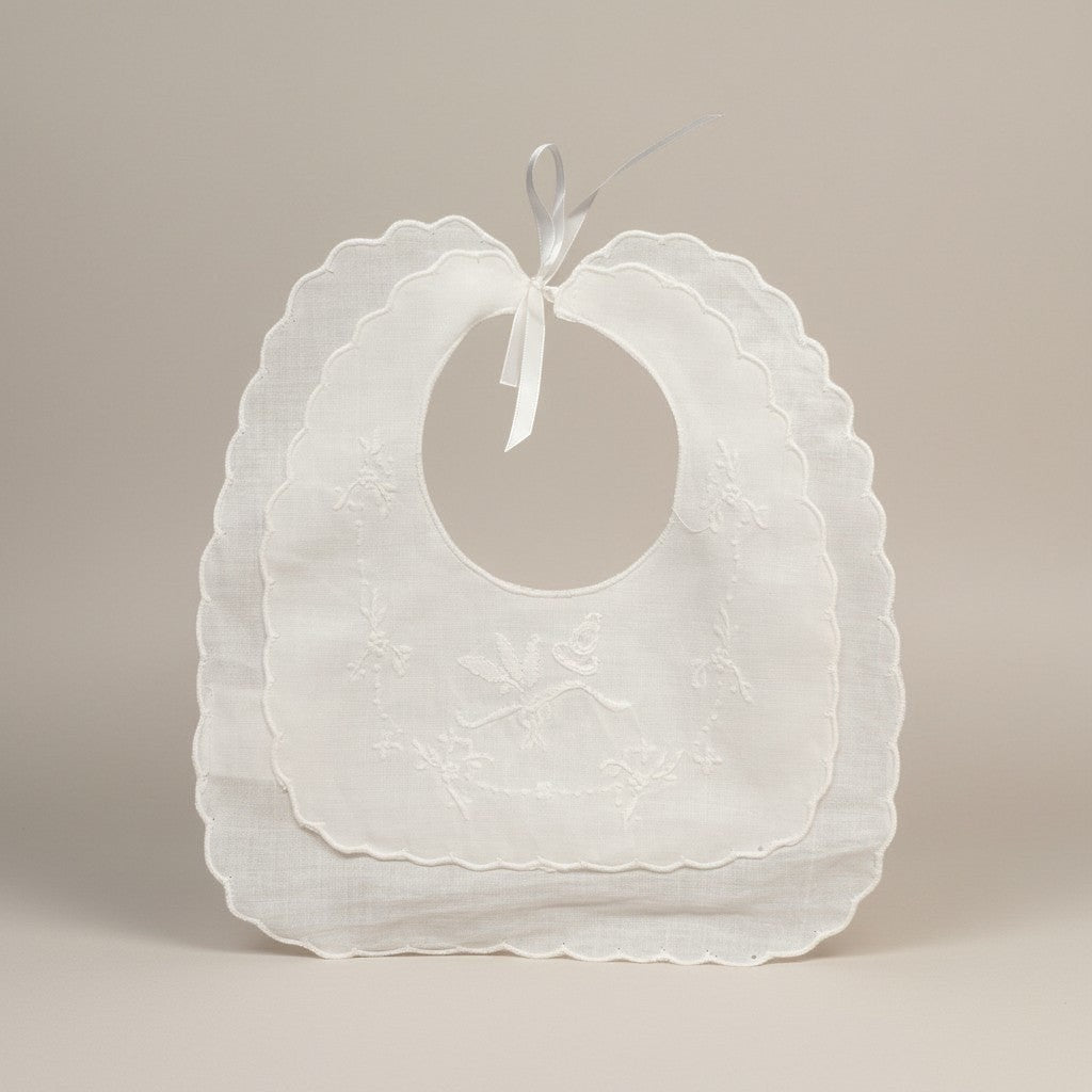 White baby bibs with ruffled edges on a beige background