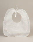 White baby bibs with ruffled edges on a beige background