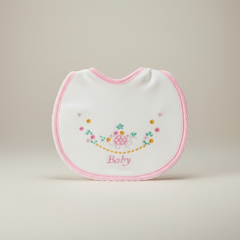 White baby bib with pink trim and floral embroidery on a beige background