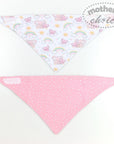 Two baby bibs with different patterns on a white background, one featuring cartoon characters and rainbows, the other pink with white polka dots.