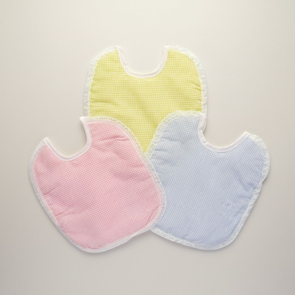 Three baby bibs in pastel colors on a light background