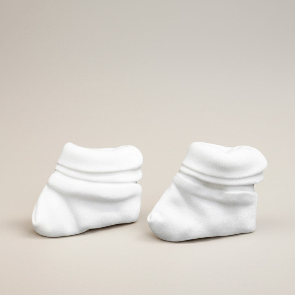 Pair of white baby socks on a beige background