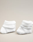 Pair of white baby socks on a beige background