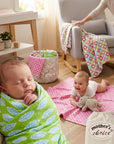 Two babies in a room with colorful blankets and a 'Mother's Choice' bag.