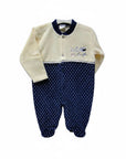 Baby onesie with cream top and navy polka dot bottom on a white background