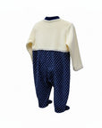 Baby outfit with cream top and navy polka dot pants on a white background