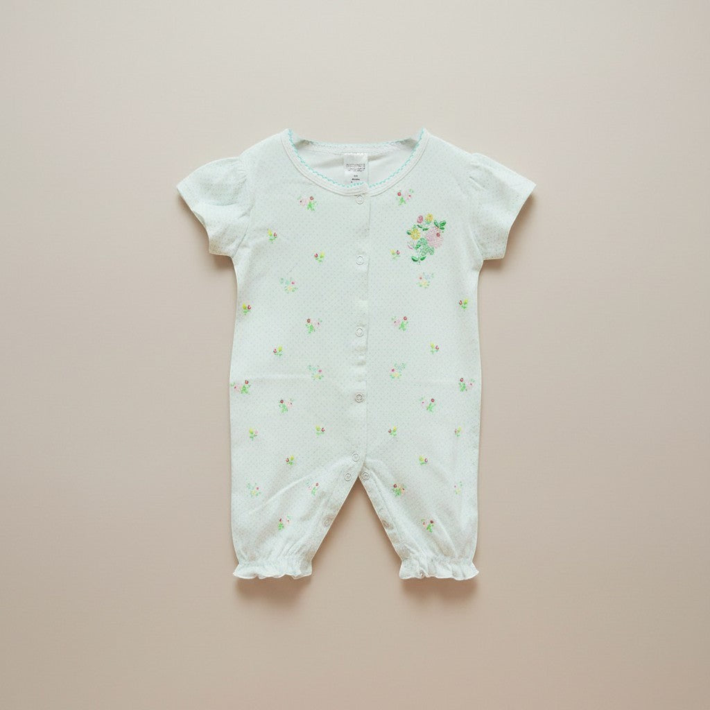 White baby romper with floral patterns on a beige background
