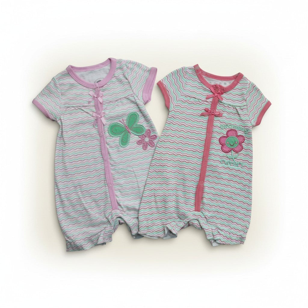 Two baby rompers with floral designs on a white background