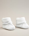 Pair of white baby socks on a beige background