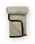 Folded blanket with brown trim on a white background