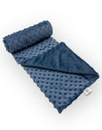 Blue textured blanket rolled up on a white background