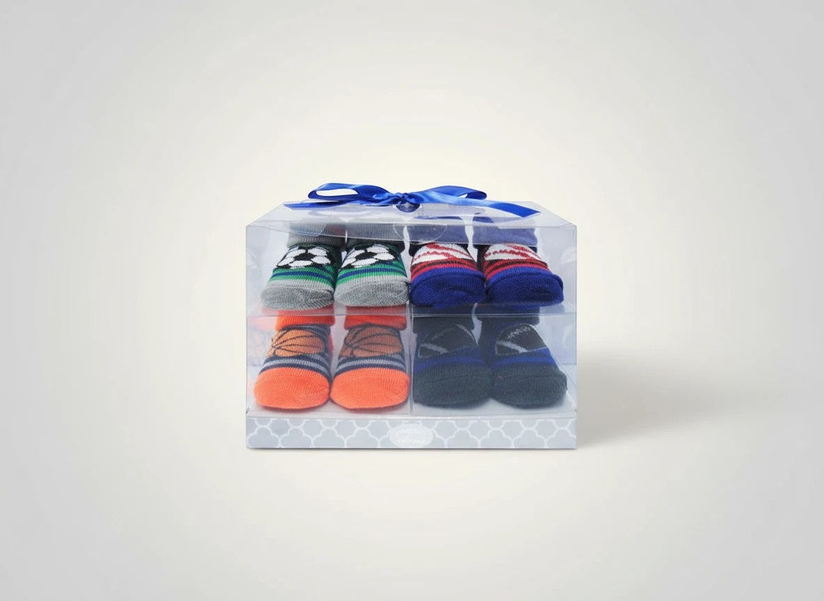 Stork And Baby 4 pack baby socks gift set with soccer, basketball, and striped designs in a clear box with blue ribbon.