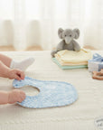 Stork And Baby blue patterned muslin bib for baby feeding and drool protection. Soft, breathable fabric.