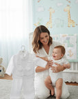 Stork And Baby Mothers Choice white long-sleeve christening suit for boys displayed next to a smiling baby and mother.
