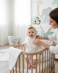 Stork And Baby white long-sleeve christening suit with tailpiece worn by a baby boy in a nursery setting.