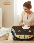 Stork And Baby brown polka dot nappy bag with a woman packing baby clothes and a puppy nearby.