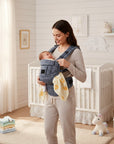 Stork And Baby 3-way elegant baby carrier in grey plaid with adjustable straps, holding a baby. Soft fabric.